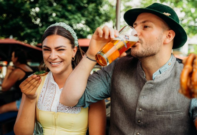 Paar im Biergarten am Marienplatz beim Der Pschorr München – Mann trinkt Pschorr Bier, Frau genießt Brotzeit mit Schnittlauchbrot.